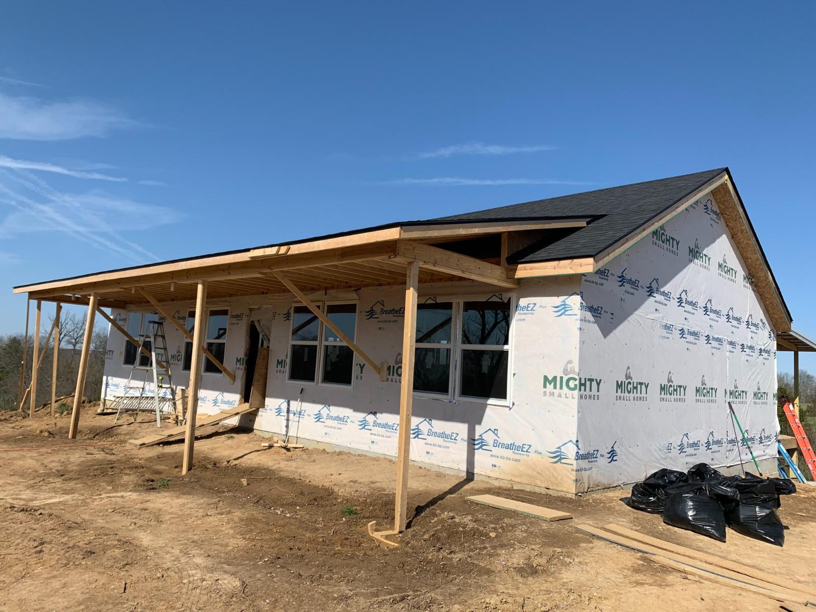 A partially constructed house with exterior sheathing and roof framing in place.