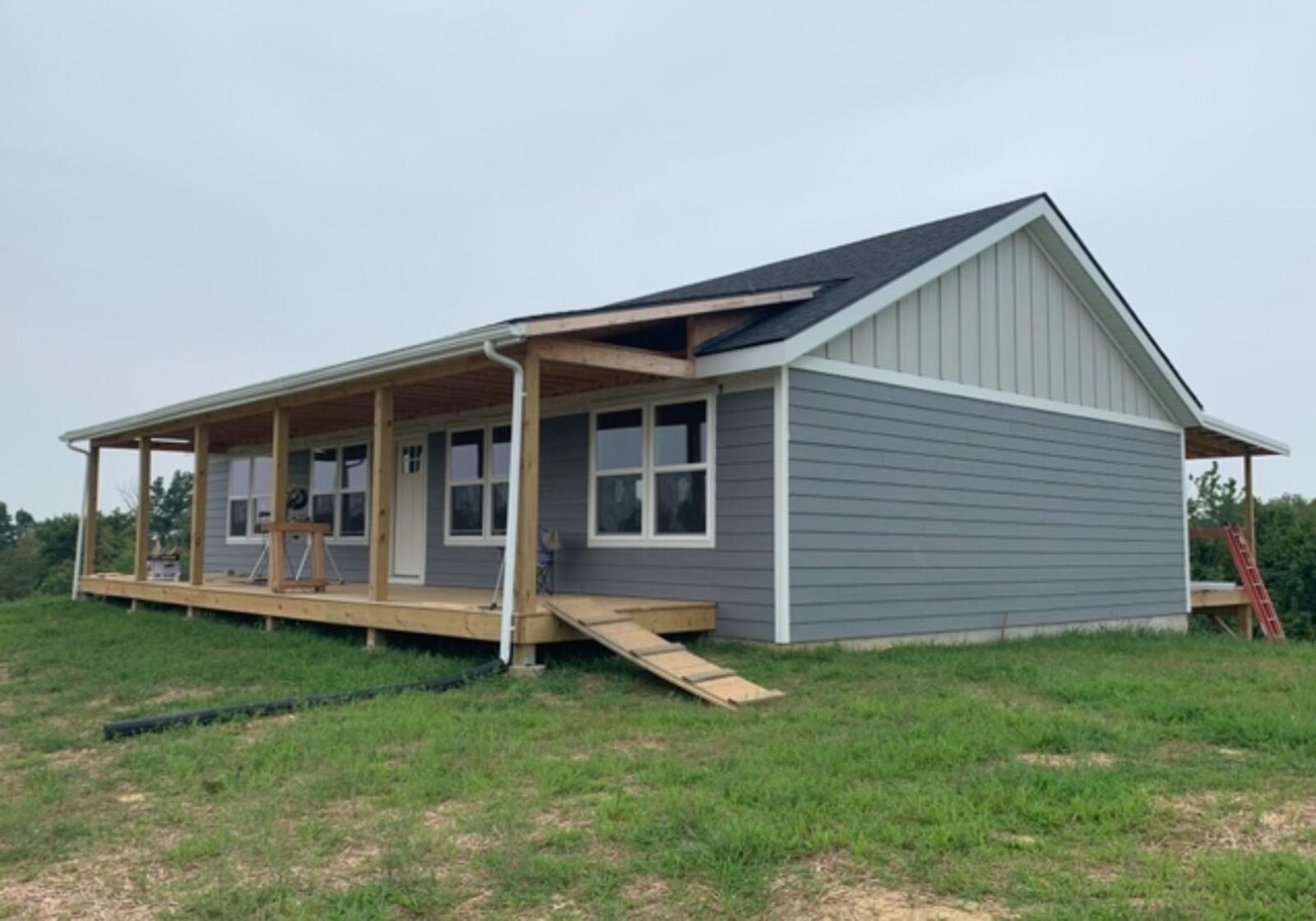A single-story home with a covered front porch, gray siding, and a gabled roof.